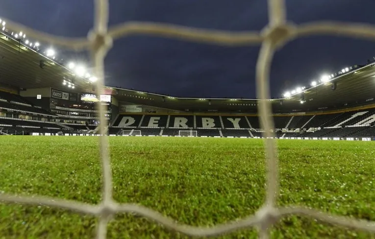 Góc nhìn độc đáo về sân Pride Park qua lưới khung thành, cho thấy không khí trận đấu sôi động