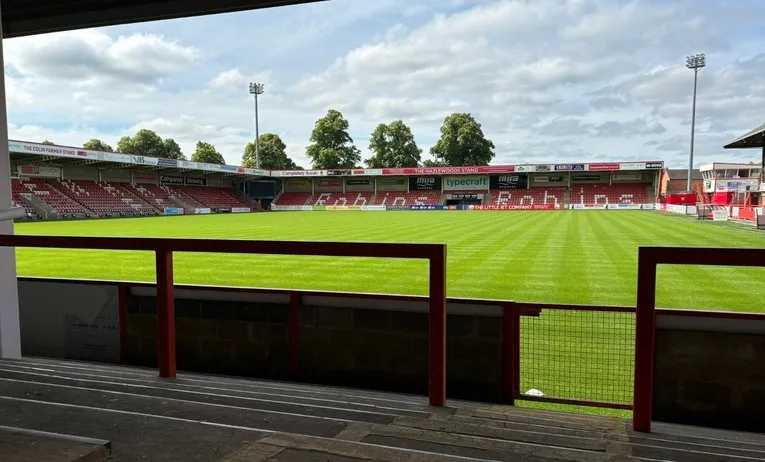 Góc nhìn từ khán đài đứng Speedy Skips Stand tại sân Whaddon Road