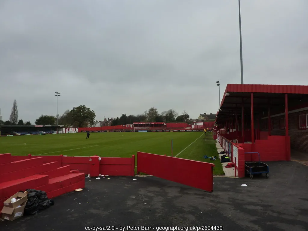 Hình ảnh cận cảnh sân cỏ và khán đài chính sân Impact Arena (North Street), cho thấy khu vực thi đấu tại Alfreton
