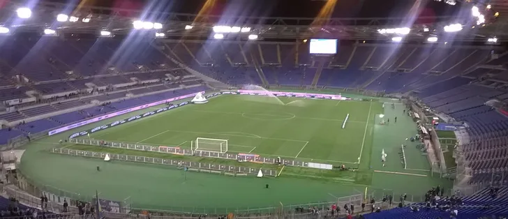 Sân vận động Stadio Olimpico trống trải nhìn từ khán đài, thể hiện tầm nhìn toàn cảnh sân cỏ