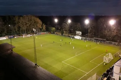 Toàn cảnh sân vận động Beveree Stadium, sân nhà của câu lạc bộ Hampton & Richmond Borough, với các khán đài và khu vực sân cỏ xanh mướt dưới ánh nắng.