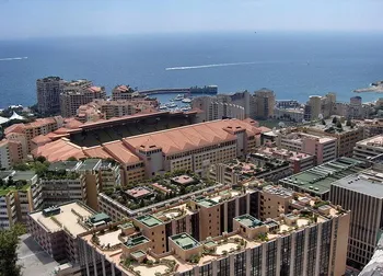 Toàn cảnh sân vận động Stade Louis II tại Fontvieille, Monaco, với kiến trúc hiện đại và đường chạy điền kinh bao quanh sân cỏ.
