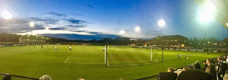 Tổng quan sân Blackwell Meadows dưới ánh đèn pha vào ngày thi đấu, cho thấy không khí sôi động và bố cục sân.